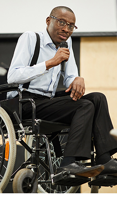 Un homme assis dans un fauteuil roulant donne un discours