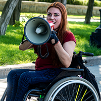 Woman in a wheelchair shouting into a megaphone