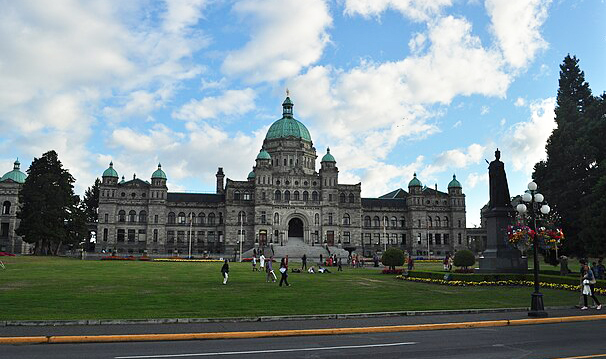 The British Columbia Legislature building, a grey stone building with a green arched roof and green arched turrets