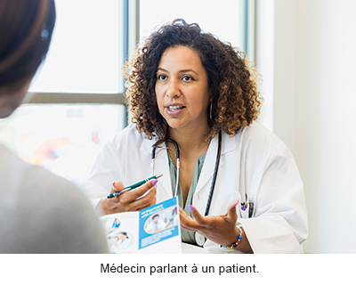 Un médecin portant une blouse blanche, assis derrière un bureau, parlant à un patient
