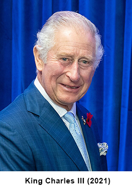 King Charles III, an older man with white hair, wearing a blue suit and smiling