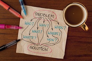 Napkin next to a coffee cup with the words problem, who, why, when, what, where, what if, how, and solution