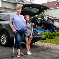 Smiling HVMP recipient Michelle and her daughter Aime in front of their modified car