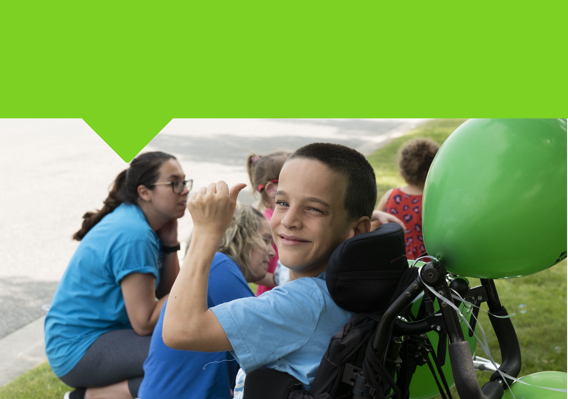 Un enfant souriant dans un fauteuil roulant montre un pouce levé