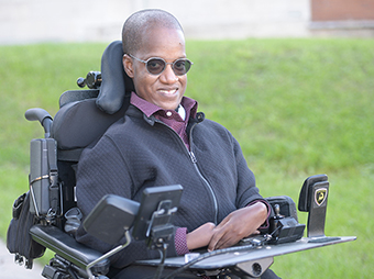 Gift Tshuma - smiling sitting in his wheelchair outside